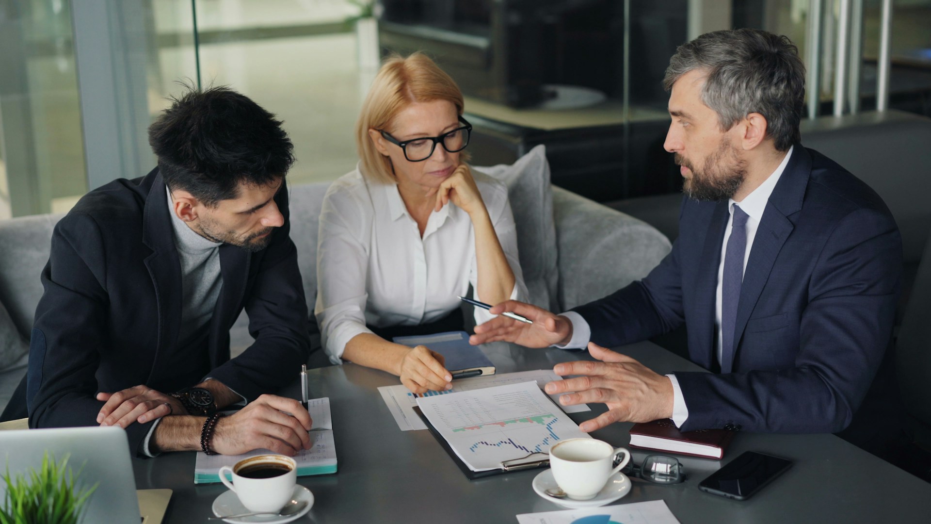 An advisor walking two clients through charts and figures at a meeting table