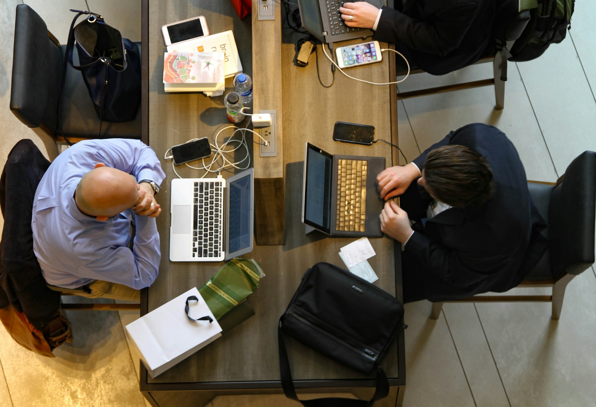 People working at desks in a warmly lit open-plan office, seen through floor-to-ceiling windows