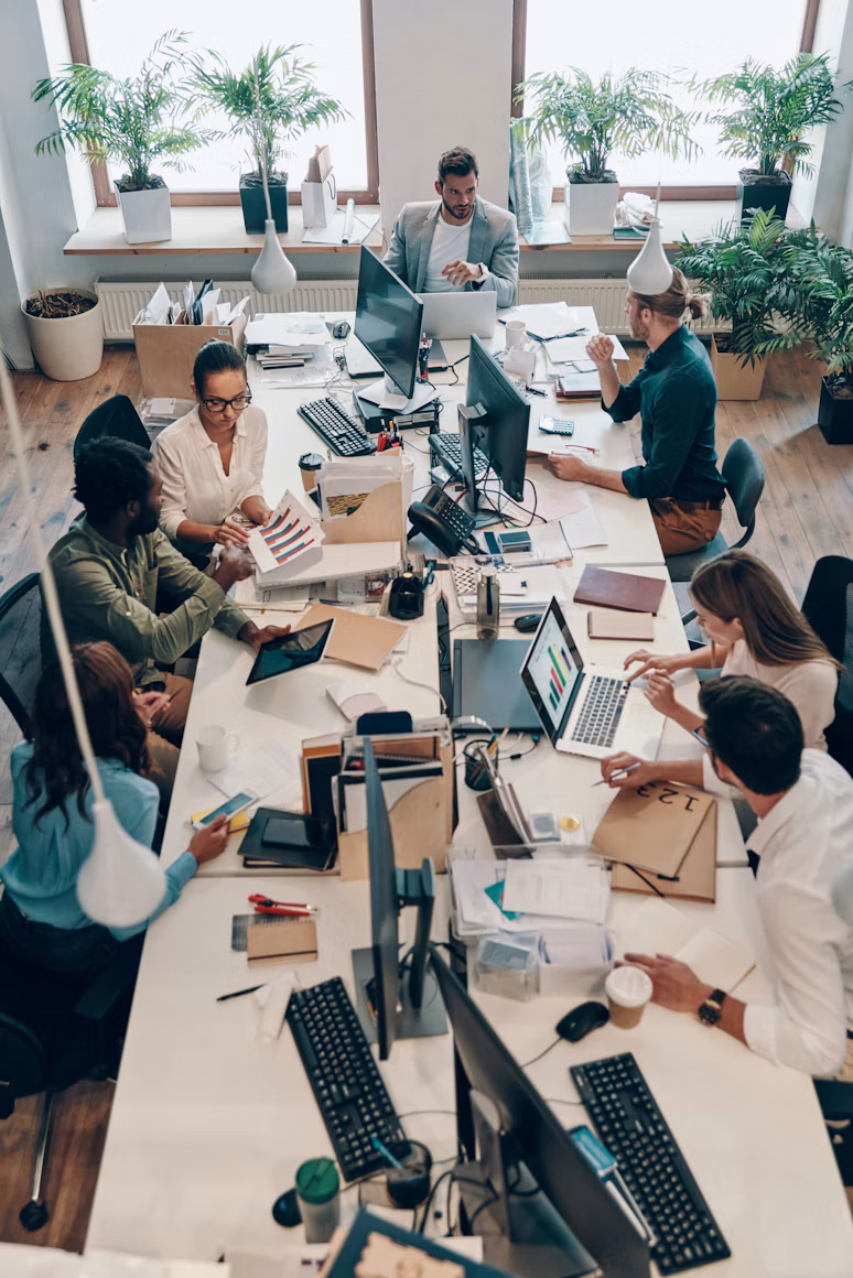 Overhead view of a team working together at long shared desks in a bright office
